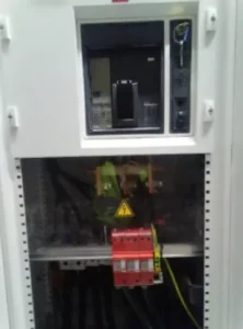 Armoire électrique industrielle avec câblage, disjoncteurs rouges et signalétique de danger haute tension.